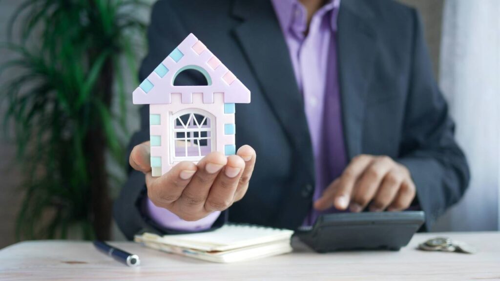 A businessman holding a miniature of a house
