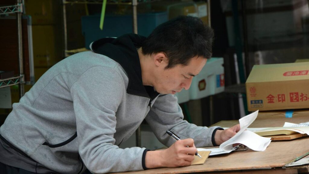An Asian man reading documents and taking notes