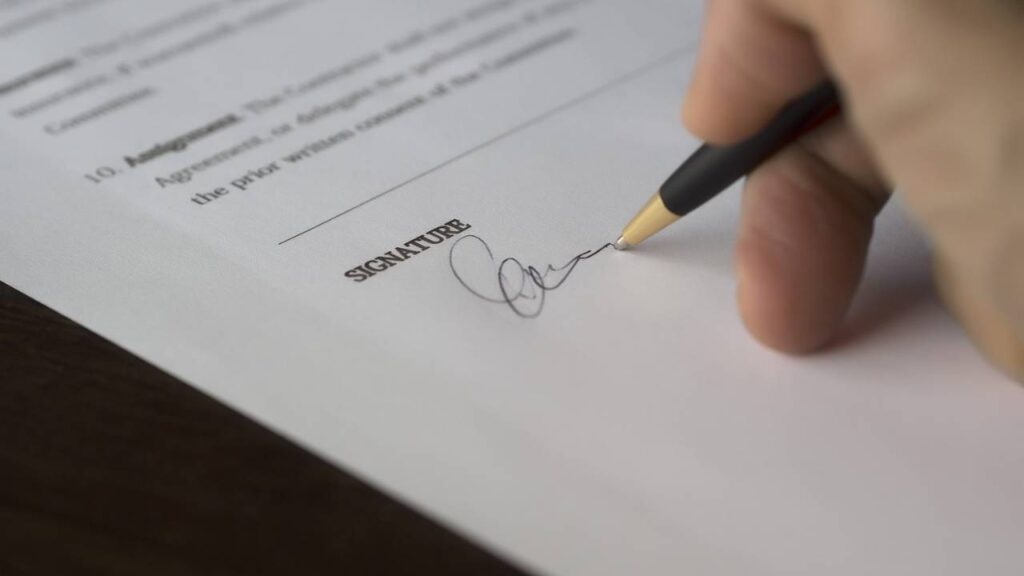 A person using a pen to sign a document