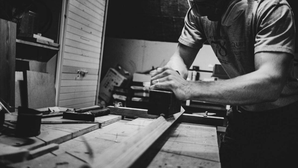 A black and white photo of a man working with wood in his workshop