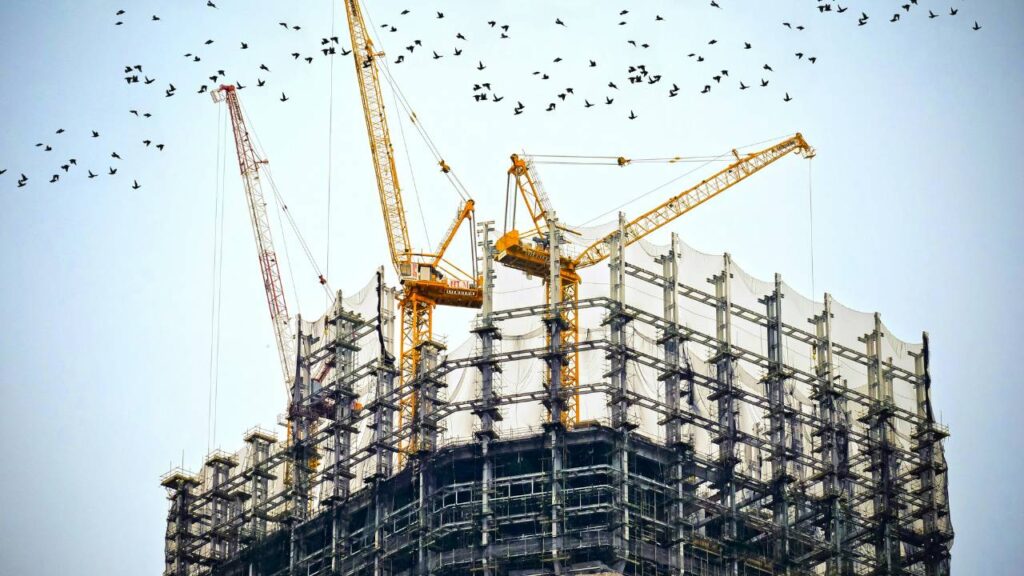 Several cranes on top of a building that's being built 