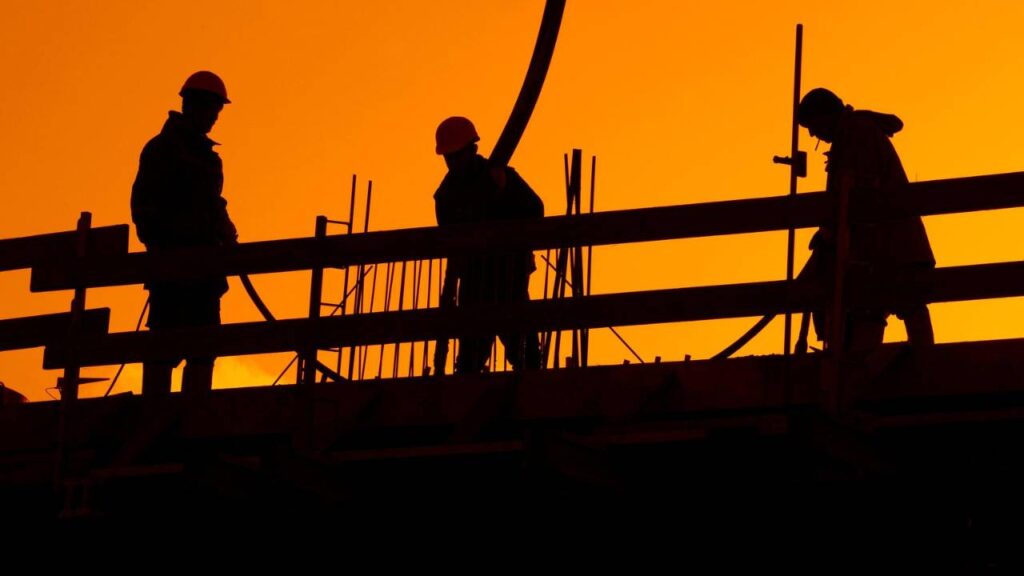 A photo of three construction workers taken at sunset 