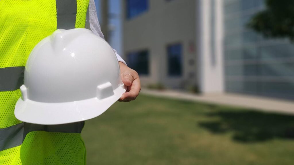 A photo of a person holding a white safety helmet 