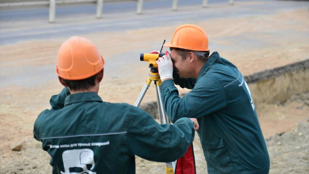 Two construction workers using a total station on site